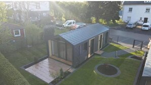 A modern house with a flat roof, a small front yard, and a driveway.