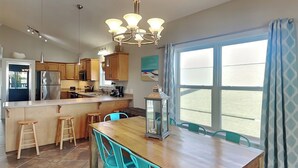 Una cocina moderna con armarios de madera, una isla central con taburetes y una mesa de comedor con sillas.
