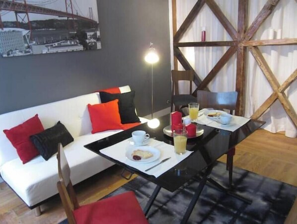Relax in this stylish living space with a sofa, dining table, and large window offering a view of the city.