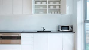A modern kitchen with white cabinetry, a built-in microwave, and a dishwasher. - Amazing Place by Liverpool St Station (London)
