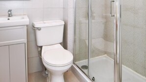 A modern bathroom with a toilet, sink, and glass-enclosed shower. - Impeccable 2-bed Apartment in London (London)