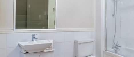 Ein modernes Badezimmer mit Waschbecken, Toilette und Dusche in Weiß.