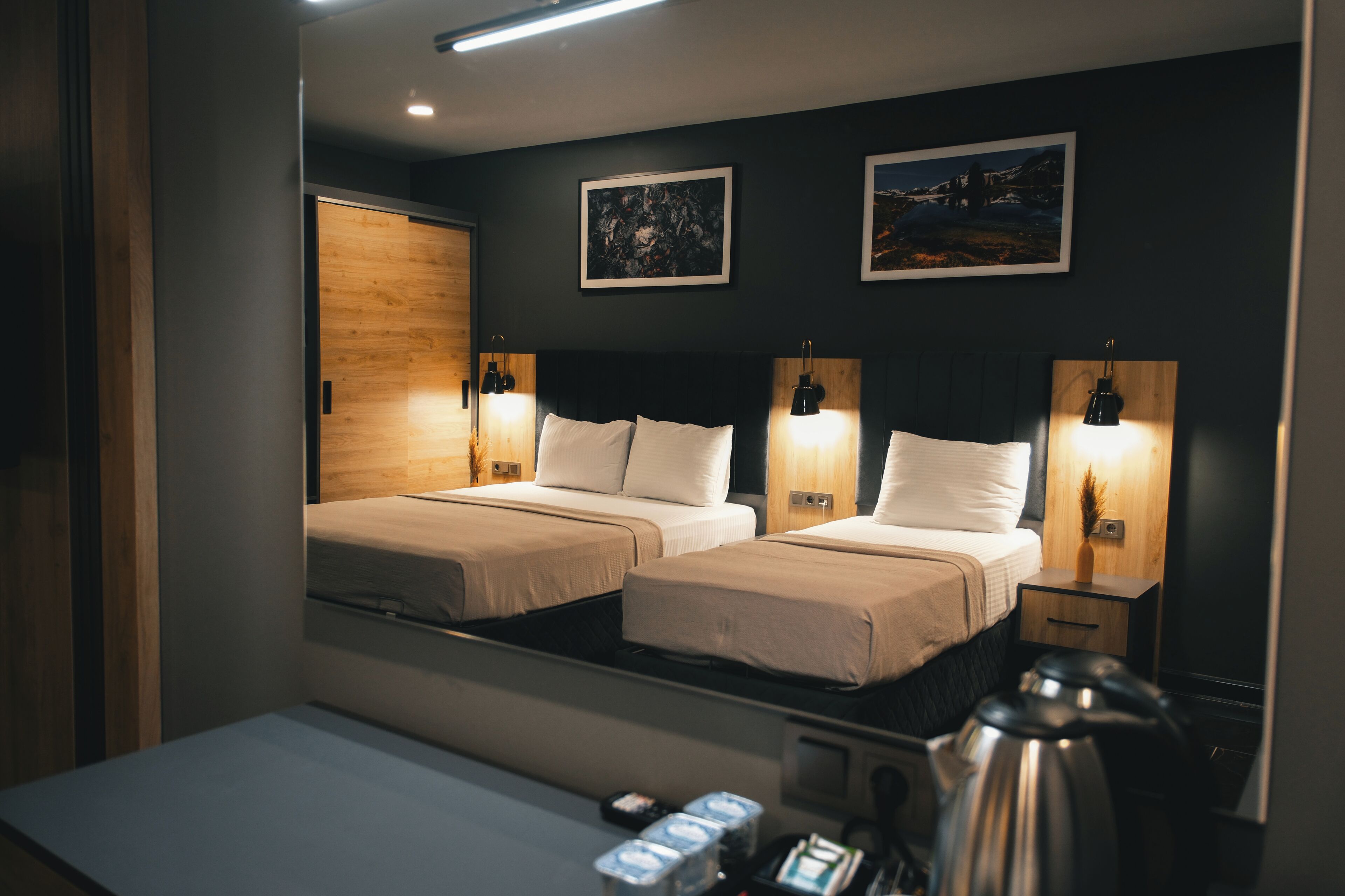 A hotel room with two beds, a large mirror, and bedside lamps.