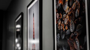 A hallway with framed artwork on the wall, including a picture of the Eiffel Tower and another with a floral design.