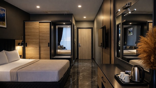 A modern hotel room with a large bed, a vanity with a mirror, a flat-screen TV, and a coffee maker on the dresser.
