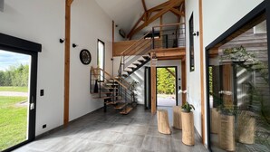 A modern interior with a wooden staircase, a large window, and potted plants.