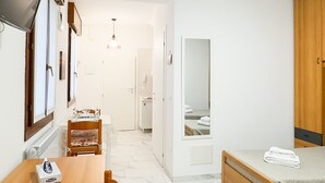 A hotel room with a wooden bed, a small bedside table, a mirror, and a view of the bathroom.