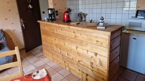 Une cuisine équipée d’un plan de travail en bois, d’une machine à café, d’une bouilloire et d’un four à micro-ondes.