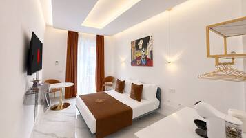 Una habitación de hotel moderna con cama, escritorio, silla, televisor y un cuadro en la pared.