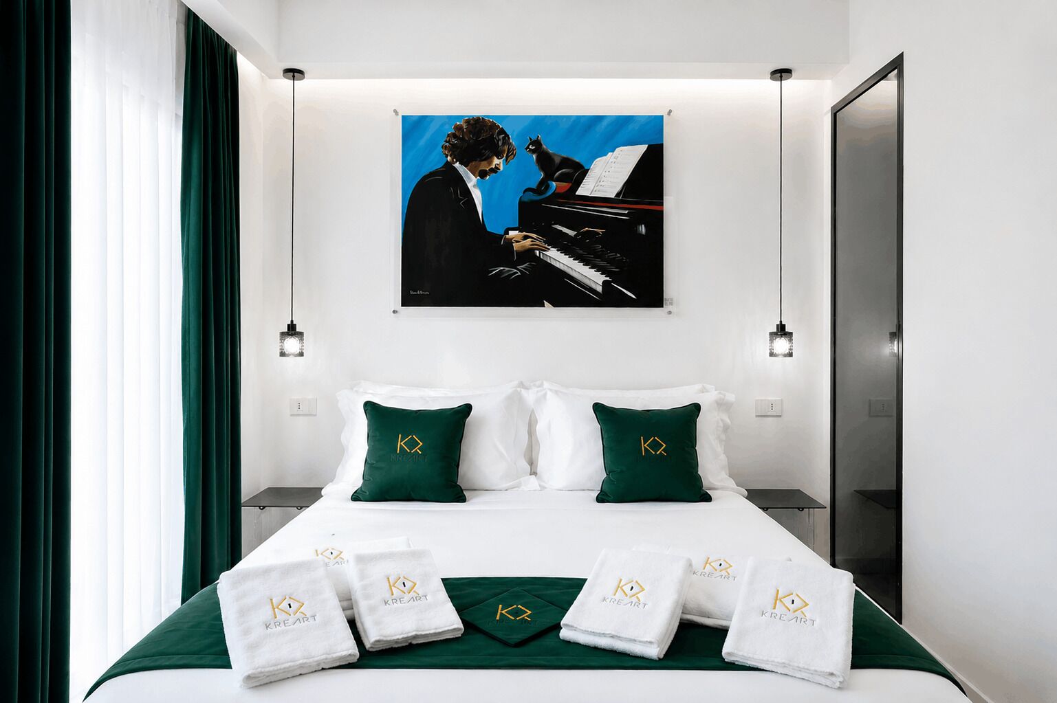 A hotel room with a bed, green pillows, a painting of a man playing a piano, and towels with a logo.