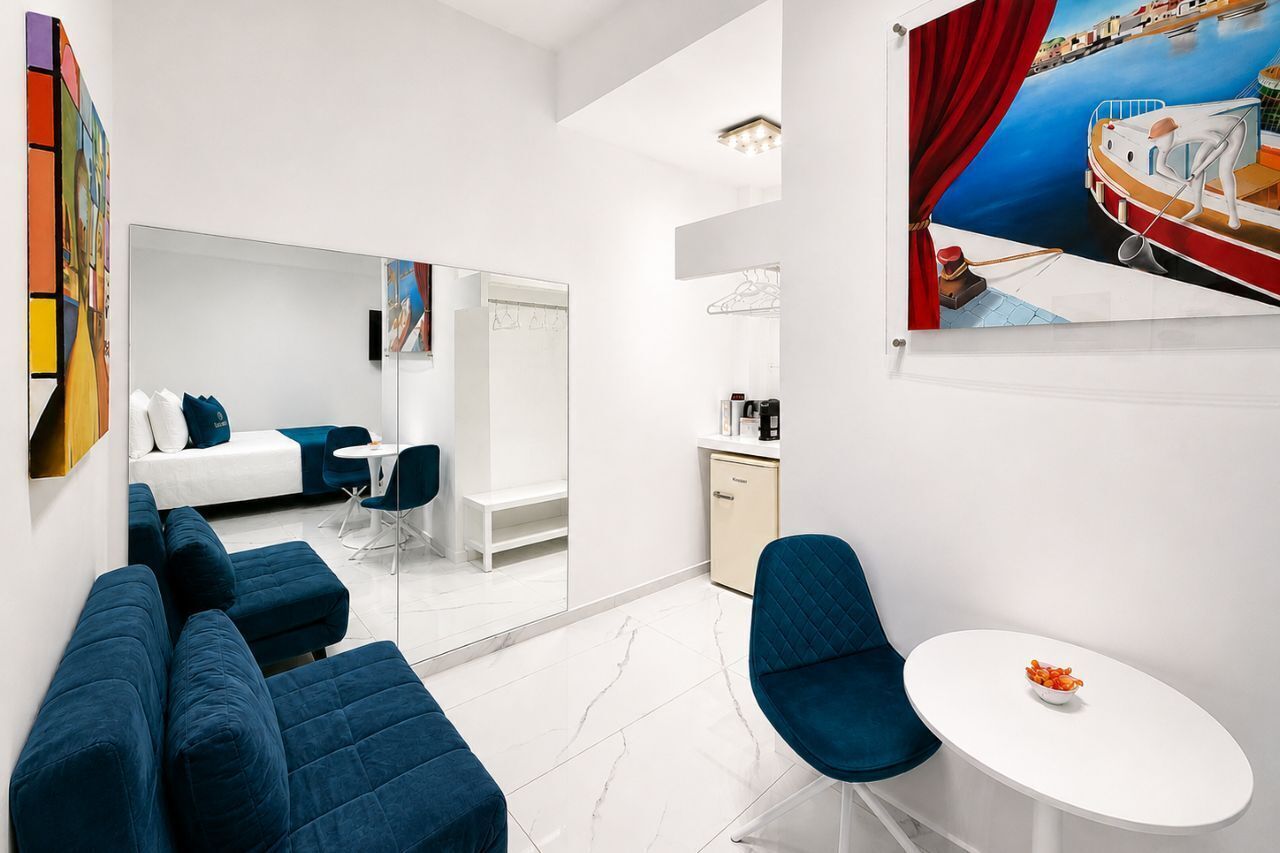 Een moderne hotelkamer met een bed, zithoek en een eettafel.