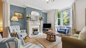 Una sala de estar con chimenea, televisor y un amplio ventanal.