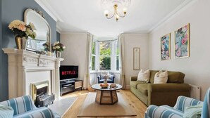 Una sala de estar con chimenea, televisor, sofá y mesa de centro.