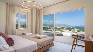 Une chambre moderne avec un grand lit, un bureau et un balcon offrant une vue sur la mer et les bâtiments.