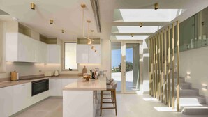 Une cuisine moderne dotée d’un îlot central, d’appareils électroménagers intégrés et de luminaires suspendus.