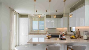 Une cuisine moderne dotée d’un îlot central, de luminaires suspendus et de tabourets de bar.