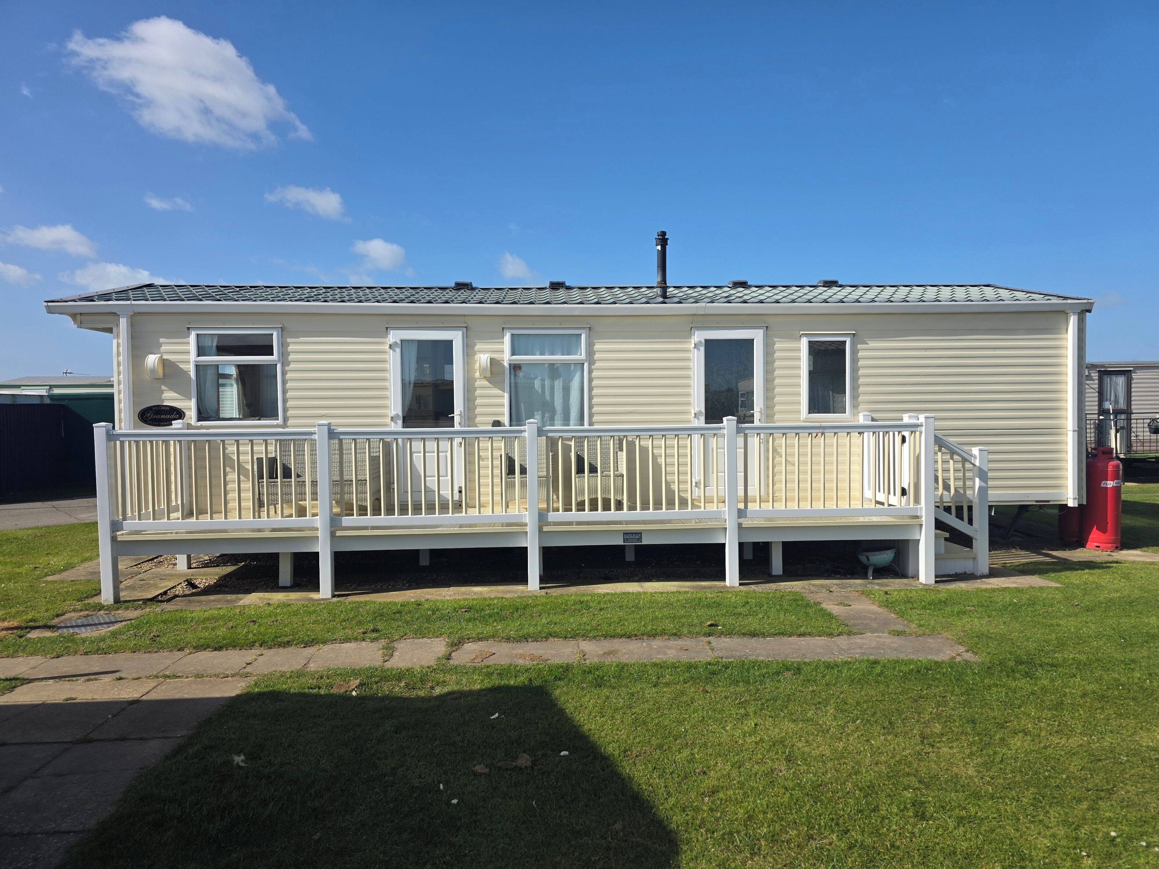 A single-story mobile home with a fenced deck and a small porch.