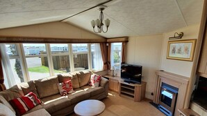 A living room with a sofa, a television, and a fireplace. - Remarkable Caravan- Chapel St Leonard's (Skegness)