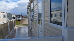 A row of mobile homes with a wooden deck and white railings. - Remarkable Caravan- Chapel St Leonard's (Skegness)