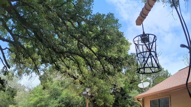 A backyard with a hot tub, a wooden deck, a white sofa, and a patio table. - Cowboy Pool Oasis (Bastrop)