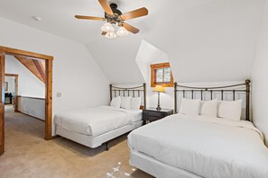 Ein Schlafzimmer mit zwei Betten, einem Deckenventilator, einem Fenster mit Jalousien und einem Nachttisch mit Lampe.