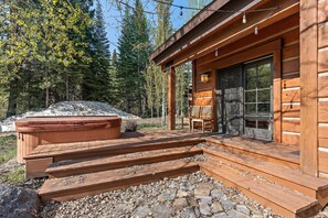 A wooden cabin with a porch, a hot tub, and a stone fireplace. - Charming Chalet on the Golf Course (Tamarack)