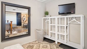 Een hotelkamer met een grote spiegel, een televisie bevestigd aan een witte console en een kleine plant op de console.