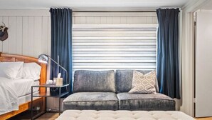 Een slaapkamer met een bed, nachtkastje, bank en een bench.