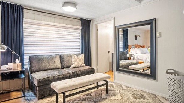 Een moderne slaapkamer met een bank, een zitbankje, nachtkastje en een grote spiegel.