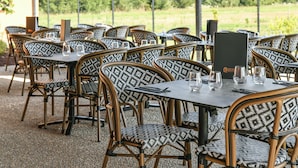Un área de comedor al aire libre con sillas y mesas estampadas, frente a un fondo de vegetación.