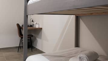 A bunk bed with a desk and chair in a room with tiled flooring.
