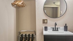 A bathroom with a white sink, black faucet, and a round mirror.