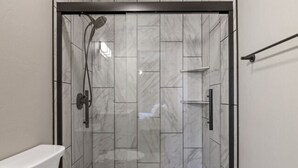 A modern bathroom with a shower enclosure, a toilet, and a sink.