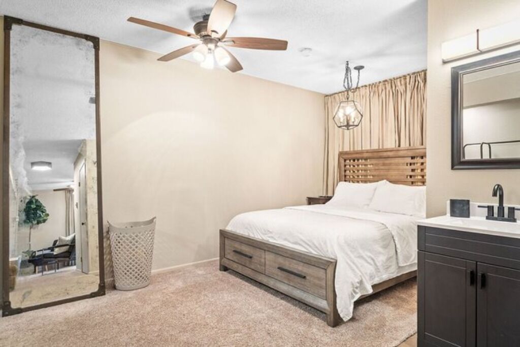 Camera da letto con un letto, una ventola a soffitto, uno specchio, un comodino e una finestra.