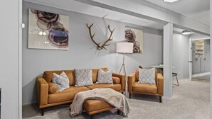 A modern living room with a brown leather sofa, patterned throw pillows, and a floor lamp.