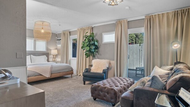 Ein Schlafzimmer mit Bett, Sessel, Schlafsofa und großem Fenster.