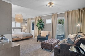 Een slaapkamer met een bed, een stoel, een bank en een groot raam.