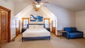 Una camera da letto con un letto grande, una ventola a soffitto, un divano blu e un quadro appeso al muro.