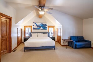 Un dormitorio con una cama grande, un ventilador de techo, un sofá azul y un cuadro en la pared.