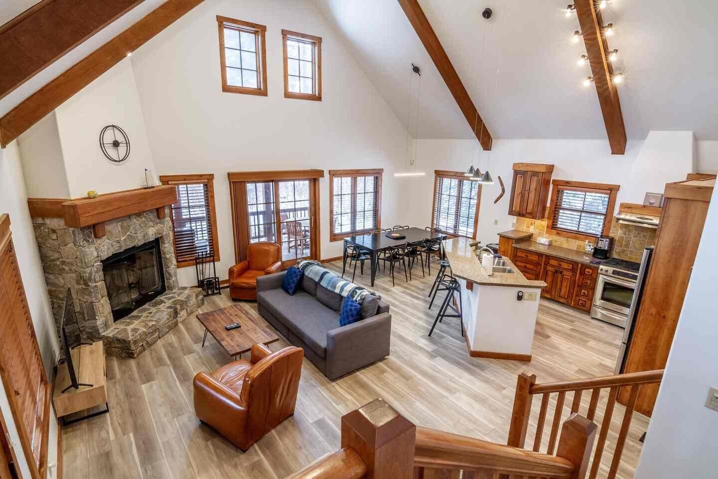 Un vaste espace de vie comprenant un foyer, une table à manger et un coin cuisine avec des meubles en bois et un plan de travail.