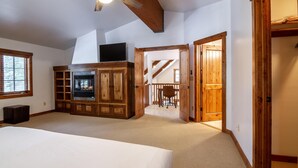 Un'ampia stanza con un letto grande, un camino, mobili in legno e una ventola a soffitto.