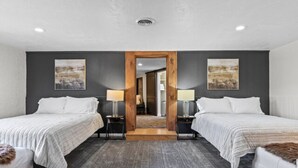 Una habitación de hotel con dos camas, un espejo grande y obras de arte en las paredes.