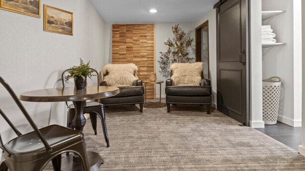 Una sala acogedora con una mesa redonda, dos sillas, un panel decorativo de madera y un mueble grande.