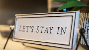 A sign with the text "LET'S STAY IN" on a metal stand.