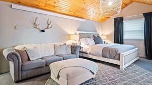Un dormitorio moderno con techo de madera, una cama, un sofá y un ciervo decorativo en la pared.