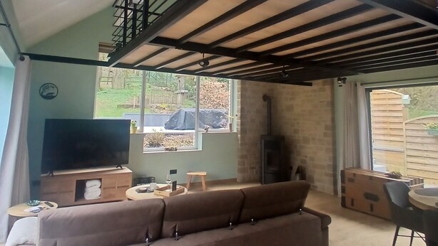 A living room with a sofa, a TV, a fireplace, and a balcony. - Évasion nature au Loft du Renard –  Calme et vue boisée près de Namur (Namur)