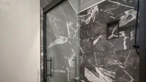 Ein modernes Badezimmer mit einer Duschkabine aus Glas, einer weißen Toilette und einer Marmor-Spritzschutzwand.