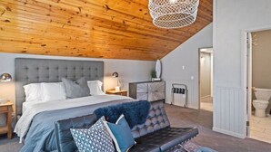 Ein Schlafzimmer mit einem großen Bett, einem Ledersofa und einer Pendelleuchte.