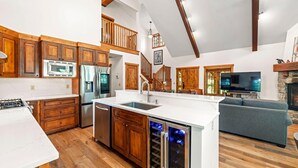 A spacious kitchen with wooden cabinets, a large island, and a built-in wine cooler.