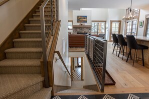 A staircase leading to a second-floor landing with a view of a kitchen area. - Comfortable 2 Bedroom Townhome  | Ski in/Ski Out (Tamarack)